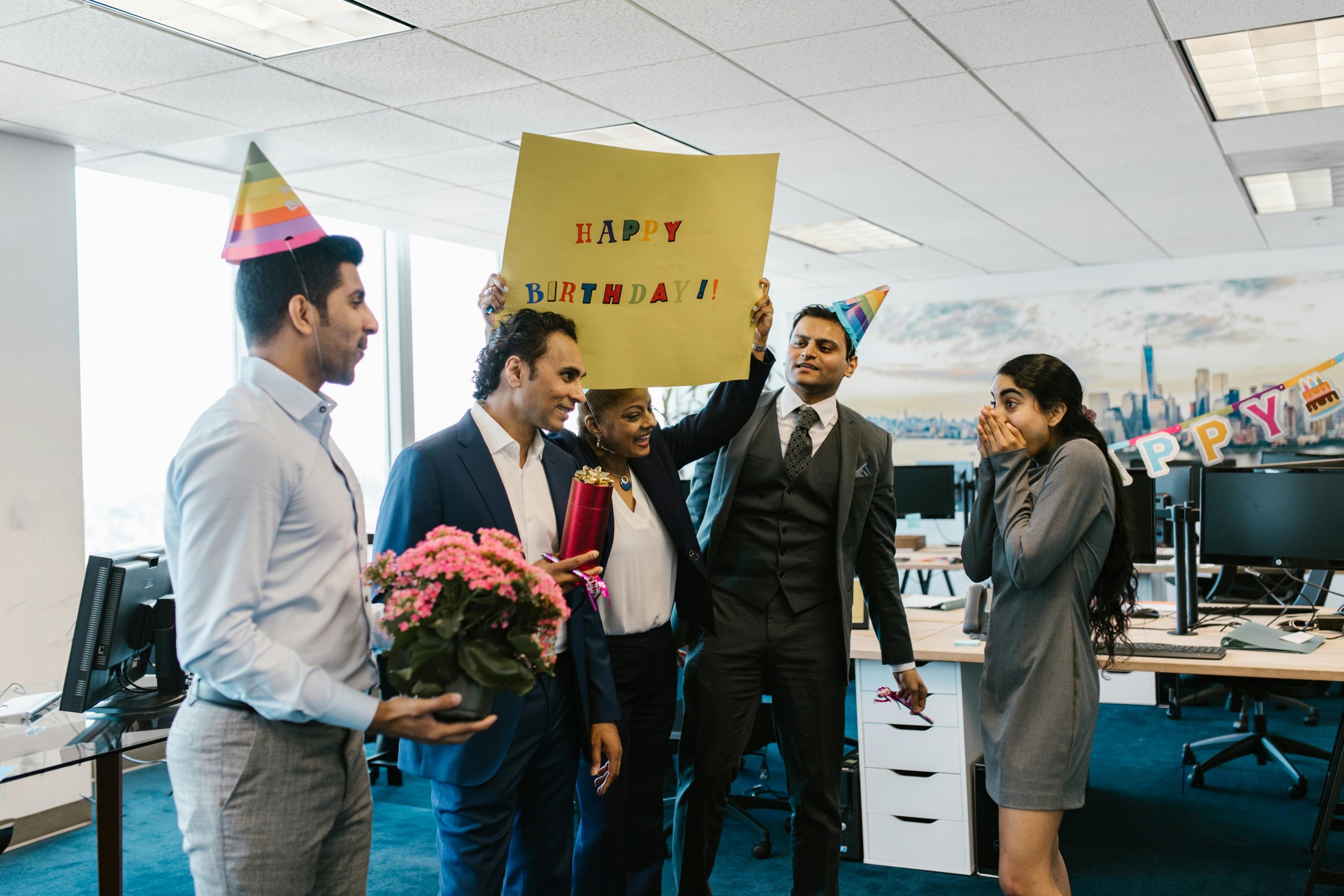 Office coworkers celebrating a birthday with flowers and cake