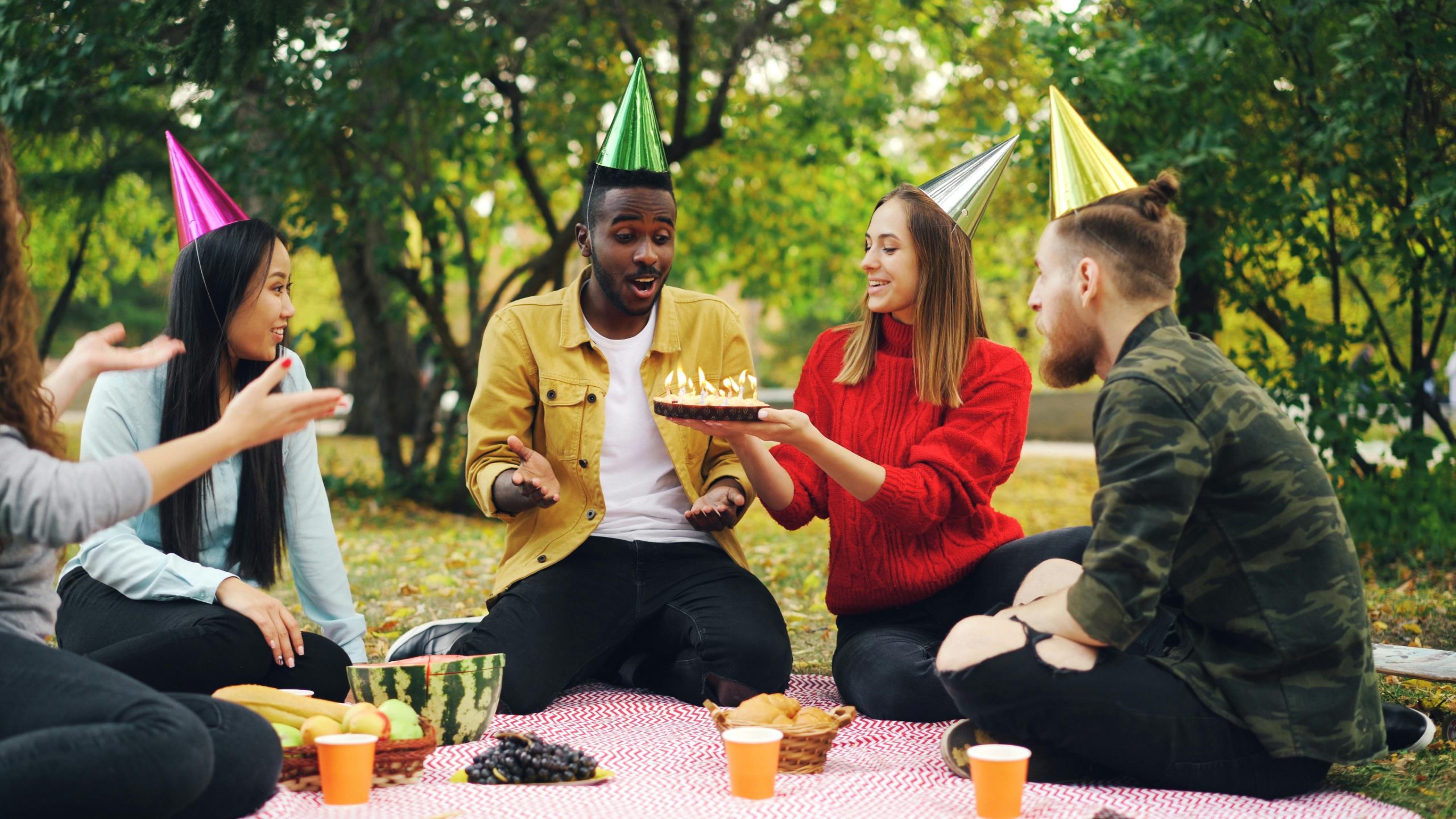 Friends celebrating together outdoors with food and cake